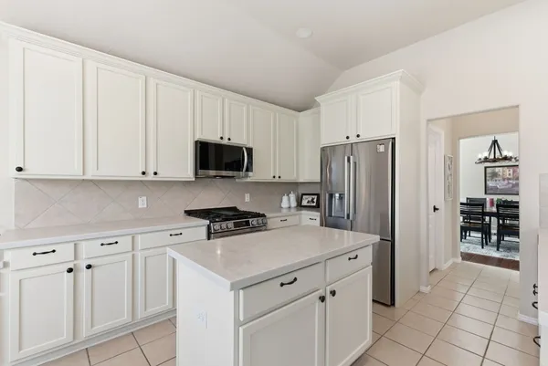 a kitchen with white cabinets and refrigerator