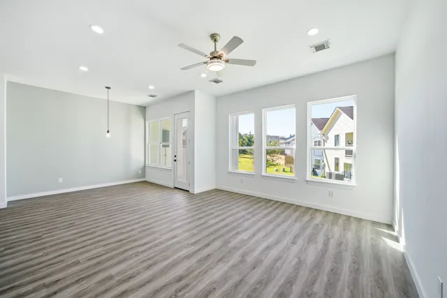 a view of an empty room with a window and wooden floor