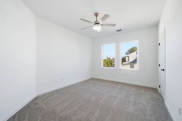 an empty room with window and ceiling fan