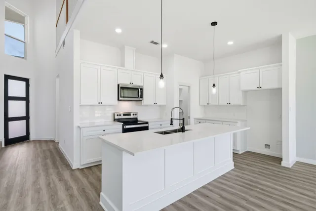 a kitchen with stainless steel appliances granite countertop a sink a stove and a wooden floors