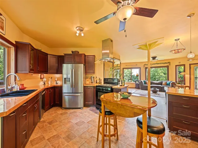 a kitchen with stainless steel appliances kitchen island granite countertop a table chairs and a refrigerator