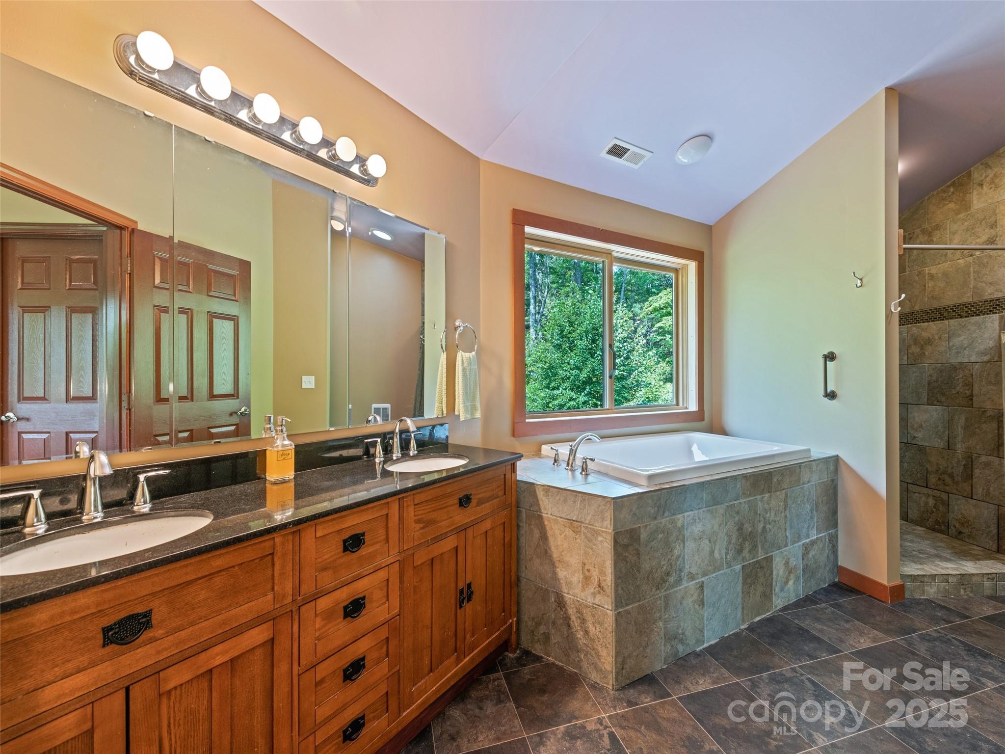 2675 Holbert Cove Road Saluda, NC 28773 - Photo 38 of 48 a spacious bathroom with a granite countertop double vanity sink a mirror and a bathtub