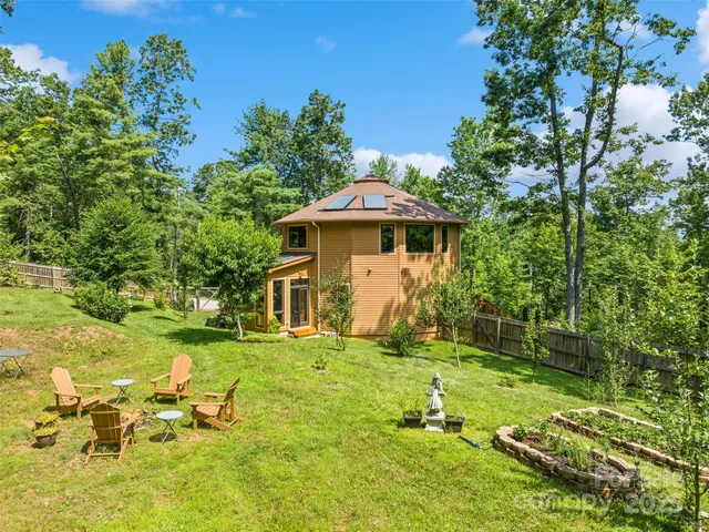 a backyard of a house with table and chairs under an umbrella