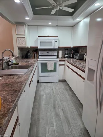 a large white kitchen with stainless steel appliances granite countertop a stove and a sink