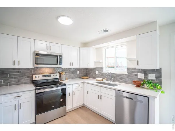 a kitchen with kitchen island granite countertop a sink stainless steel appliances and white cabinets