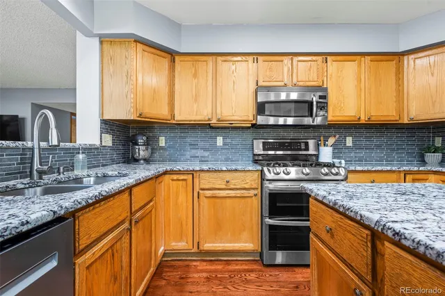 a kitchen with stainless steel appliances granite countertop a stove a sink and a microwave