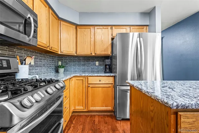 a kitchen with stainless steel appliances granite countertop a refrigerator and a stove