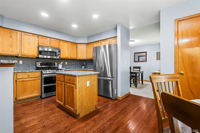 a kitchen with granite countertop wooden floors stainless steel appliances and window