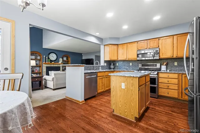 a kitchen with stainless steel appliances granite countertop a stove top oven a sink dishwasher and white cabinets with wooden floor