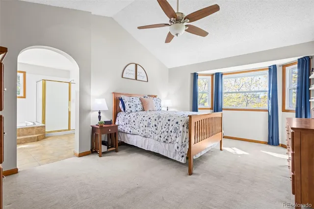 a bedroom with a bed a large window and a chandelier