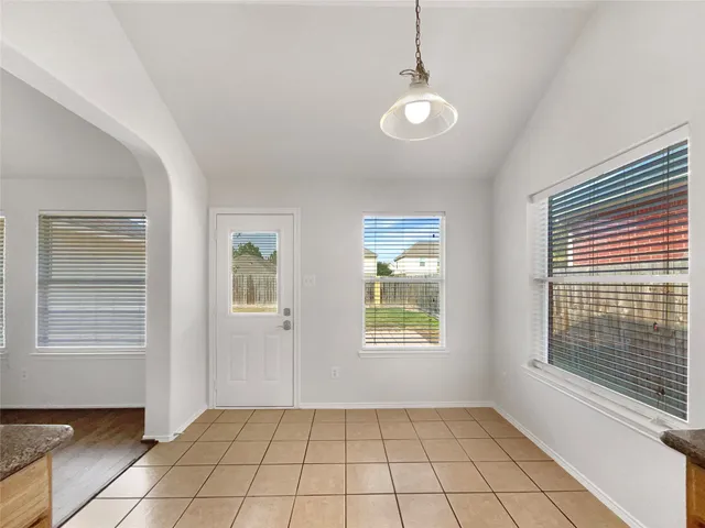 a view of an empty room with window and chandelier fan