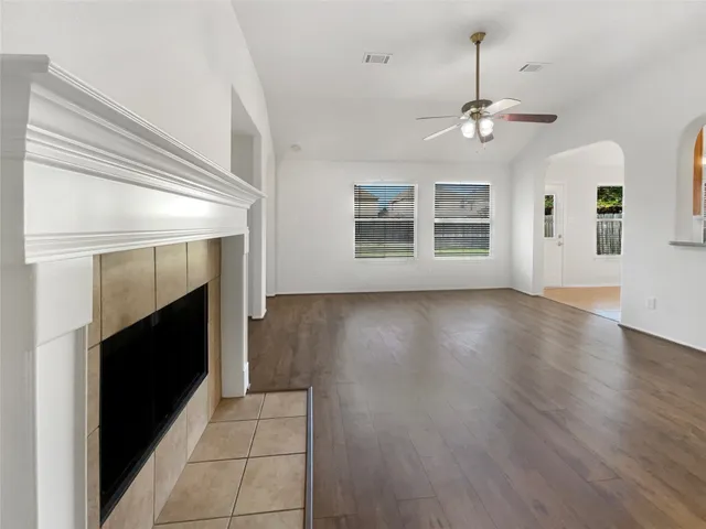 a view of an empty room with wooden floor fireplace and a window