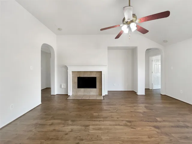 a view of an empty room with chandelier fan and fire place