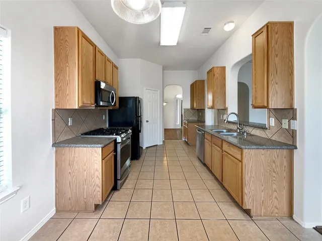 a large kitchen with stainless steel appliances granite countertop a large counter top a stove and a refrigerator