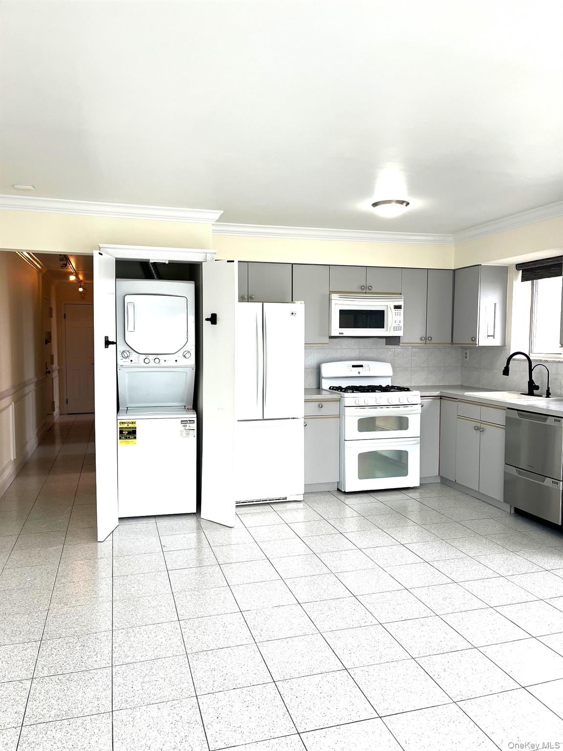 520 Ellsworth Avenue, Unit 2B Bronx, NY 10465 - Photo 3 of 21 Kitchen with gray cabinets, white appliances, ornamental molding, stacked washer and clothes dryer, and light countertops
