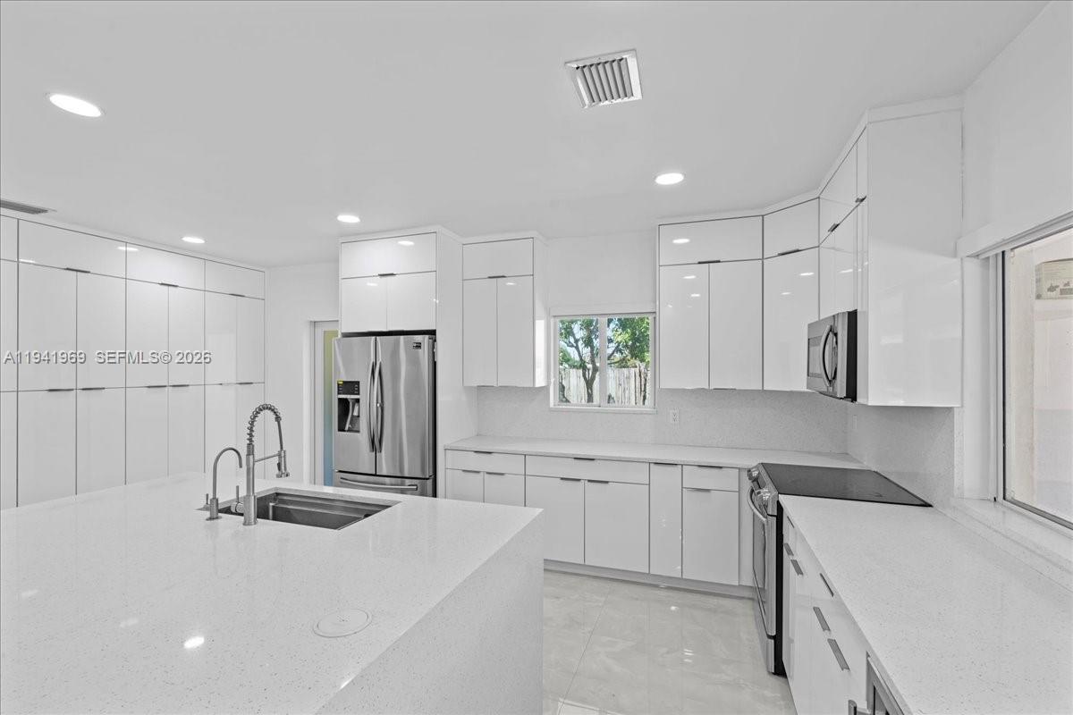 24555 Southwest 167th Avenue, Unit 1 Homestead, FL 33031 - Photo 4 of 33 a kitchen with kitchen island white cabinets and stainless steel appliances