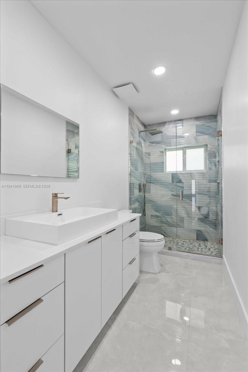 24555 Southwest 167th Avenue, Unit 1 Homestead, FL 33031 - Photo 5 of 33 a bathroom with a granite countertop sink a toilet a mirror and shower