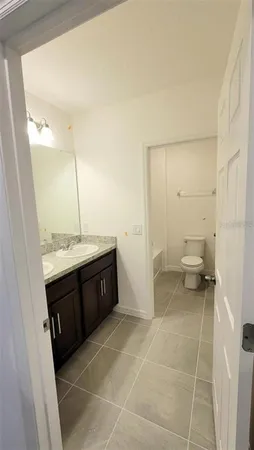a spacious bathroom with a granite countertop sink a toilet and a mirror
