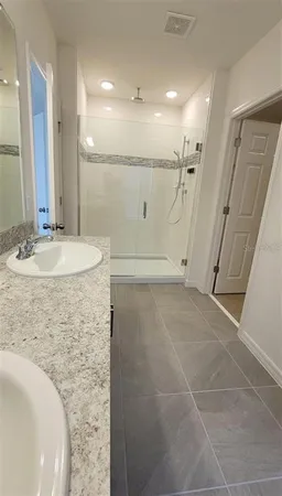 a bathroom with a granite countertop sink a mirror and a shower