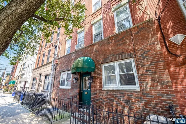 a front view of a multi story residential apartment building with a yard and potted plants