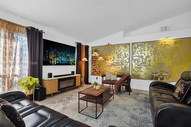 a kitchen with stainless steel appliances kitchen island granite countertop a dining table chairs and a refrigerator