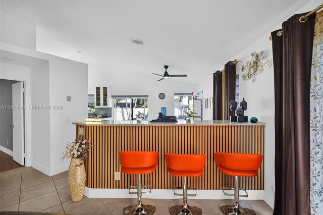 a kitchen with stainless steel appliances granite countertop a dining table chairs refrigerator and microwave