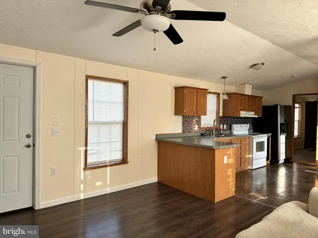 a kitchen with stainless steel appliances granite countertop a refrigerator a stove top oven a sink dishwasher and white cabinets with wooden floor