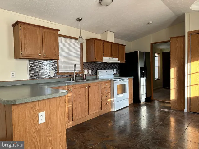 a kitchen with stainless steel appliances granite countertop a refrigerator a sink dishwasher a oven with white cabinets and wooden floor