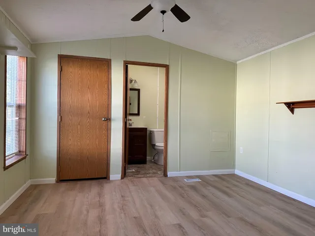 a view of an empty room with closet and a window