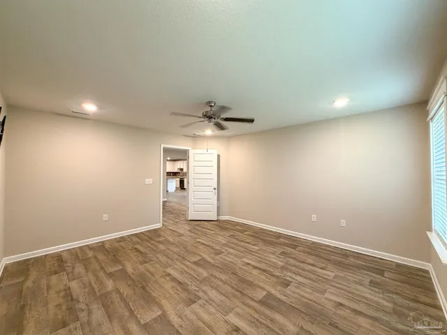 a view of empty room with wooden floor and fan