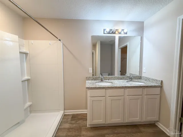 a bathroom with a granite countertop sink a mirror and a shower