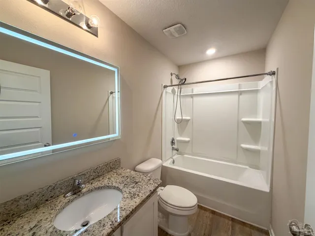 a bathroom with a granite countertop sink toilet mirror and shower