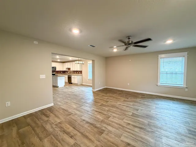 a view of a big room with wooden floor and a kitchen
