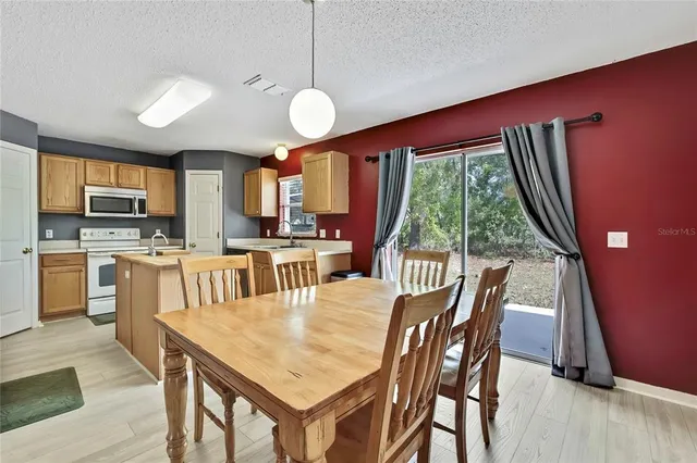 a kitchen with kitchen island a counter top space a sink a refrigerator and a view of living room
