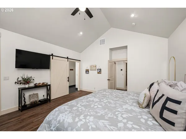 a spacious bedroom with a bed and a flat screen tv