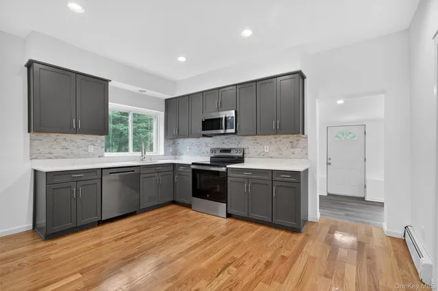 a large kitchen with granite countertop stainless steel appliances and wooden cabinets