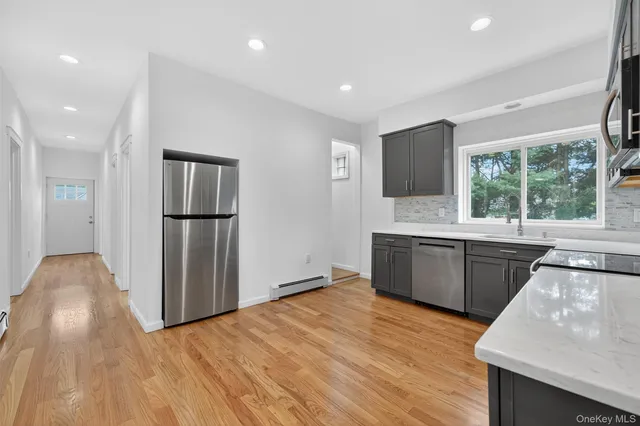 a kitchen with stainless steel appliances granite countertop a refrigerator a sink dishwasher a stove with wooden cabinets and wooden floor