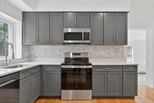 a kitchen with granite countertop a sink stainless steel appliances and cabinets
