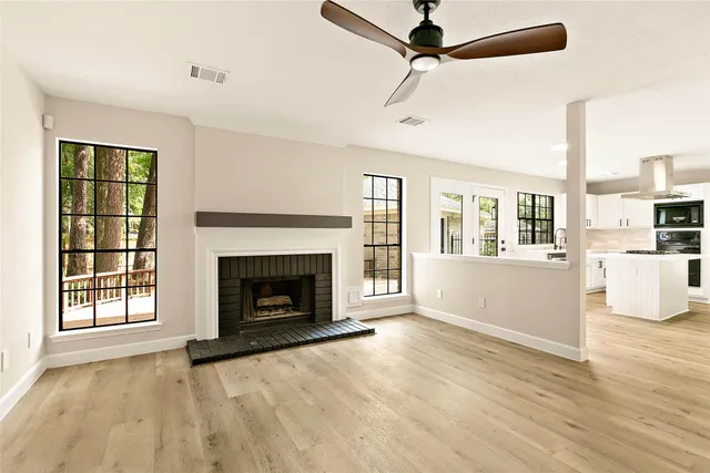 a view of a livingroom with wooden floor a fireplace and windows