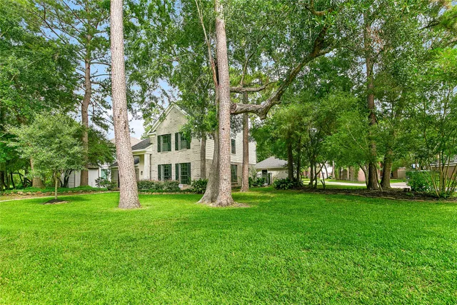 a brick house with a big yard and large trees