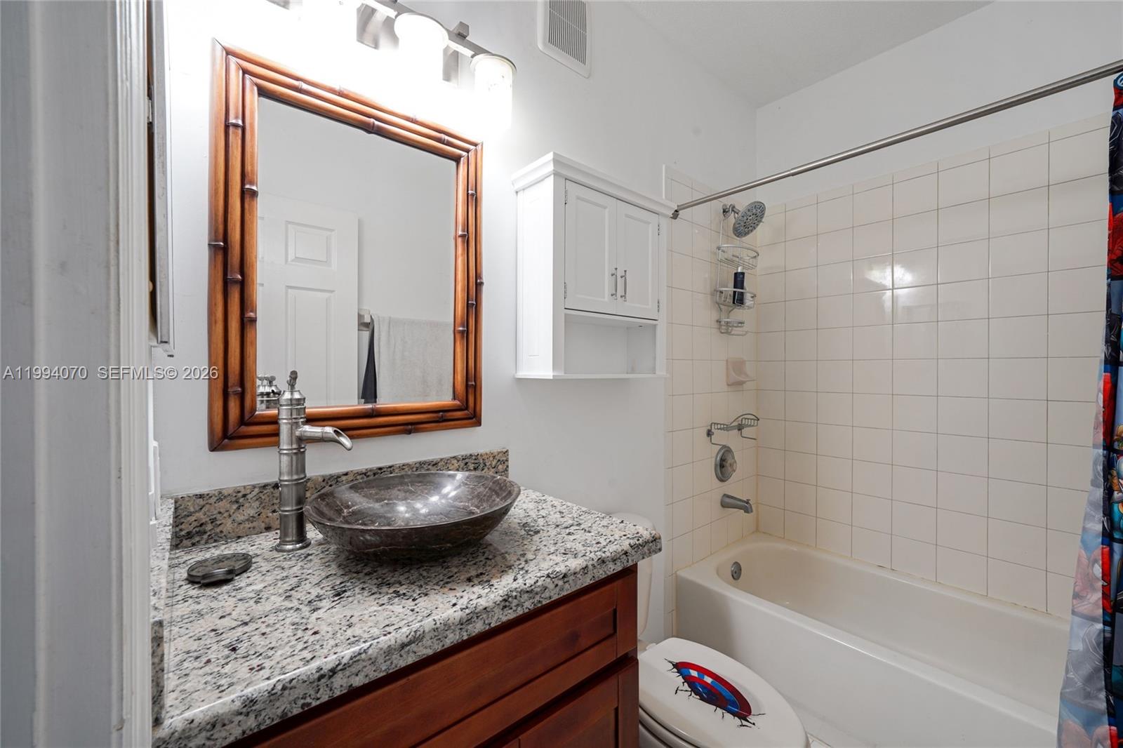 12763 Southwest 50th Street Miramar, FL 33027 - Photo 27 of 38 a bathroom with a granite countertop sink a toilet and bathtub