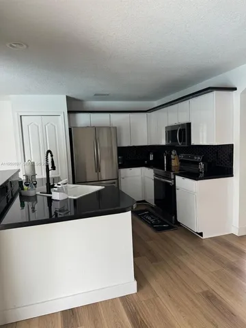 a large white kitchen with wooden floor