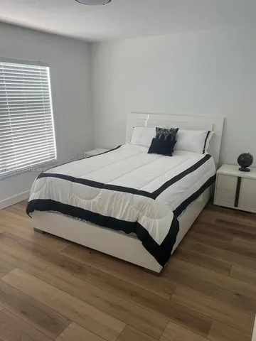 a bed sitting in a bedroom next to a window and a wooden floor