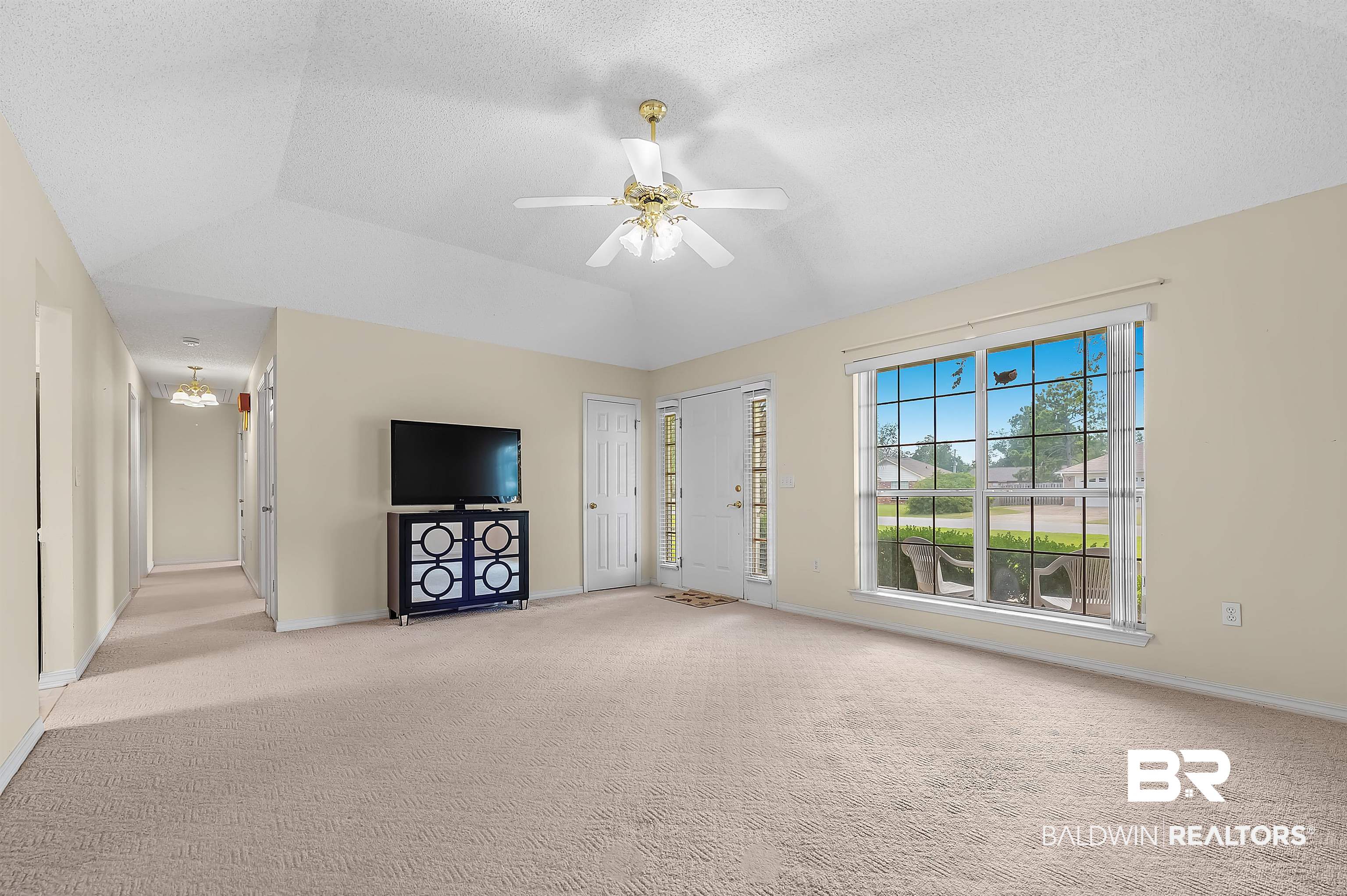 1502 Mulberry Lane Foley, AL 36535 - Photo 9 of 45 Unfurnished living room featuring light carpet, ceiling fan, vaulted ceiling, and a tray ceiling