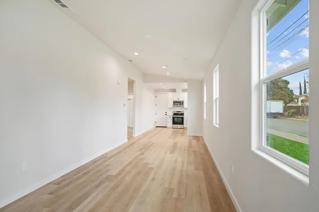 a view of empty room with wooden floor and fan