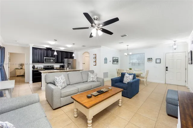 a living room with furniture kitchen view and a chandelier