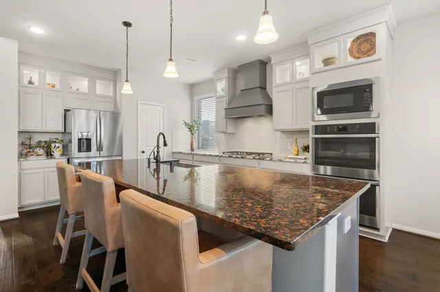 a kitchen with stainless steel appliances granite countertop a sink a stove and a wooden floors