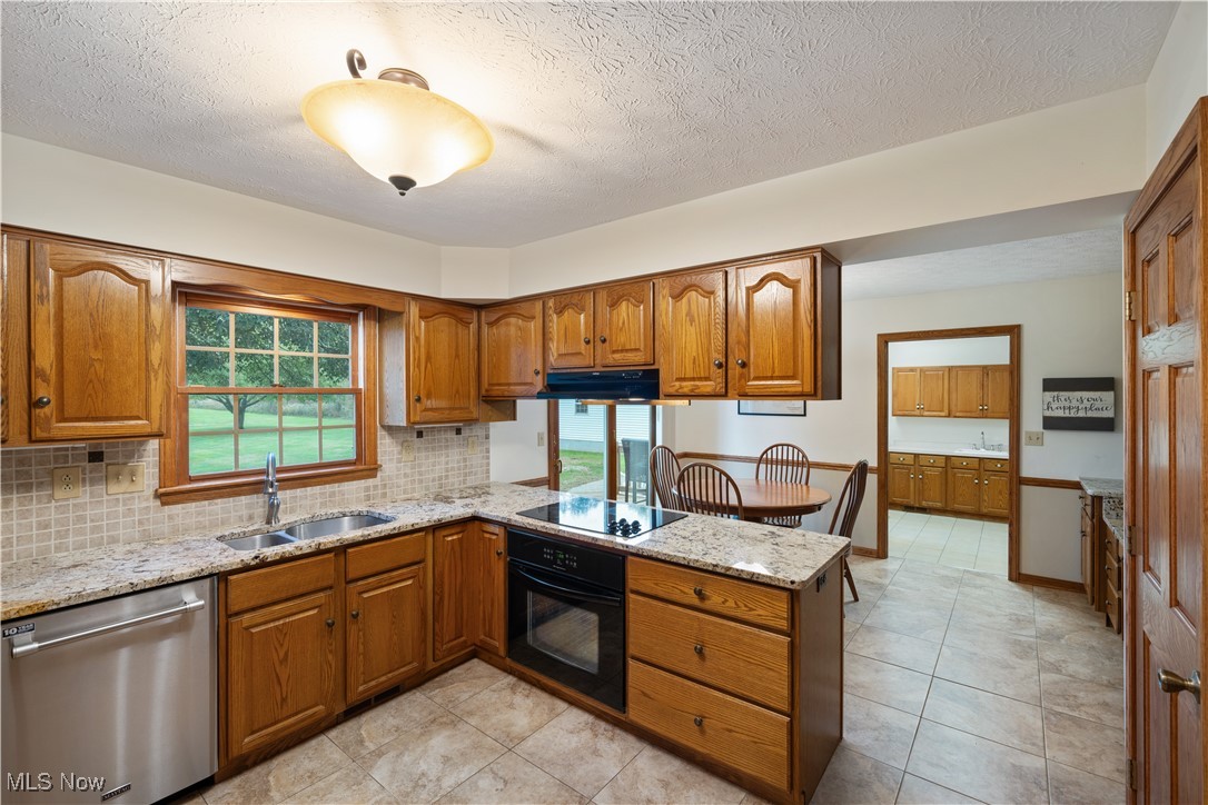 891 Station Road Valley City, OH 44280 - Photo 18 of 45 Kitchen with sink, black appliances, light stone countertops, and kitchen peninsula