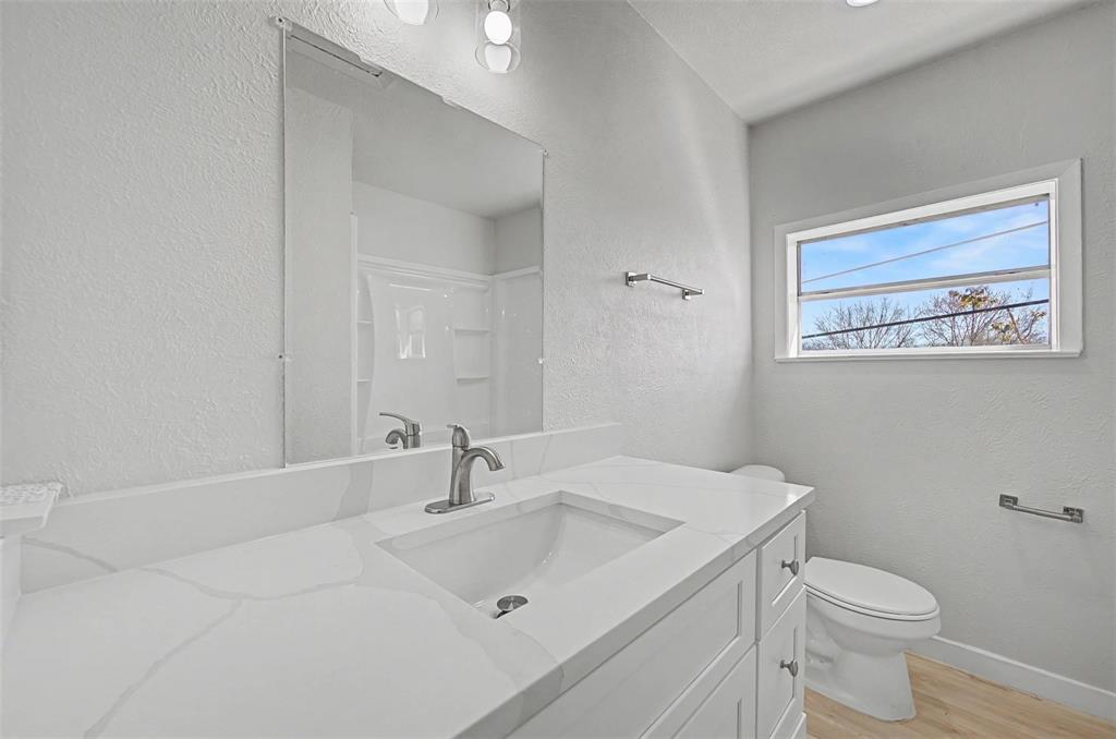9021 White Settlement Road, Unit B White Settlement, TX 76108 - Photo 4 of 19 Bathroom featuring a white vanity with a built-in sink and light-colored countertop, brushed nickel faucet, large wall-mounted mirror, and a horizontal window