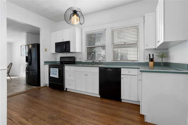 a kitchen with granite countertop a stove a sink dishwasher a refrigerator and a microwave oven with wooden floor